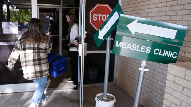 Health department staff members enter the Andrews County Health Department measles clinic...