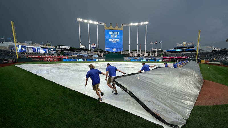 FILE: Members of the grounds crew pull the tarp after a rain delay before a baseball game...