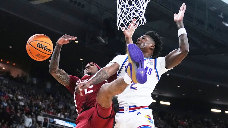 Arkansas guard Boogie Fland, left, is fouled by Kansas guard AJ Storr, right, during the first...
