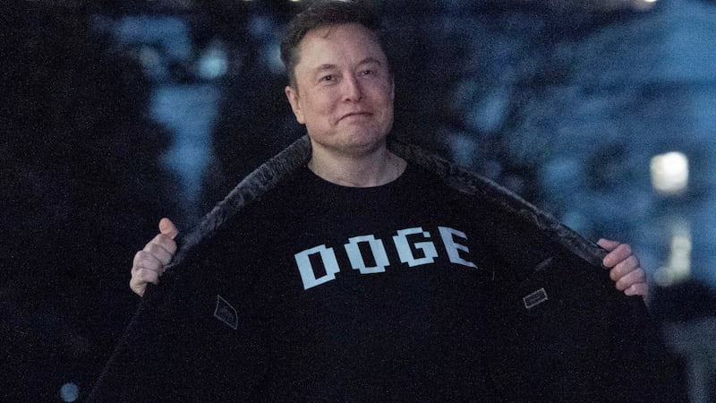 Elon Musk flashes his t-shirt that reads "DOGE" to the media as he walks on South Lawn of the...