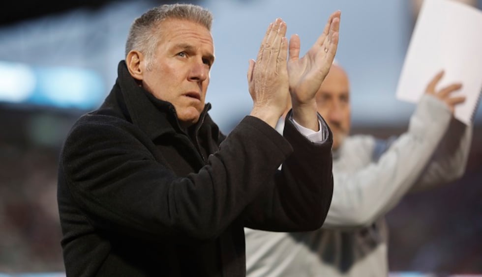 Sporting Kansas City head coach Peter Vermes acknowledges fans as he takes the pitch to lead...