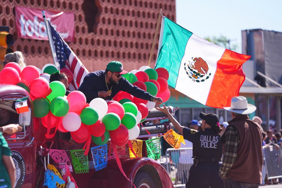 A float rider hands candy to a Dallas police officer during a Cinco de Mayo parade in the Oak...
